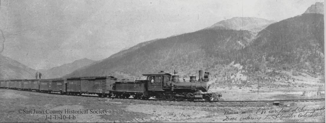 A Silverton Northern Railroad train hauls 10 carloads of zinc concentrates into Silverton, around 1925, pulled by SN #4, with two men on the third boxcar. San Juan County Historical Society photo